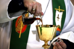 Priest pouring sacramental wine from a cruet into a chalice. 