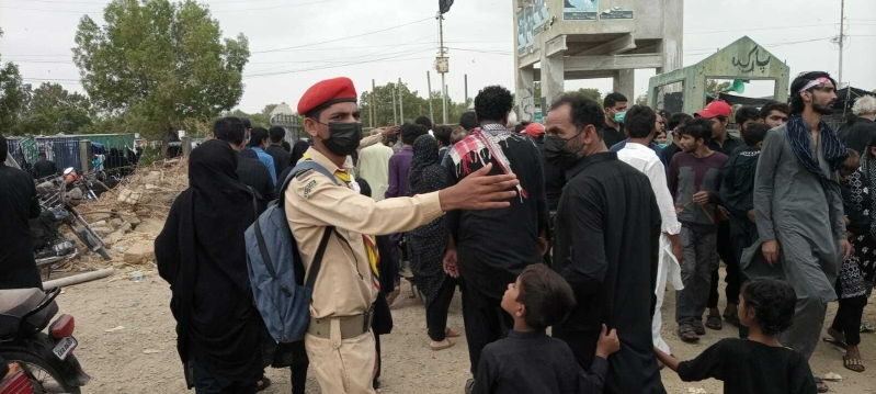 A Christian scout guides Shia mourners towards the Ashura procession in Pakistan