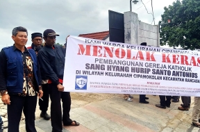 Muslim residents with banner saying they reject construction of Catholic church building in Cipamokolan village, Indonesia.