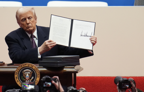 U.S. President Donald Trump holds up an executive order after signing it during an indoor inauguration parade